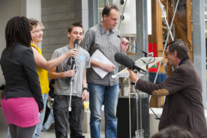 Jongeren die aan het project deelnamen worden geïnterviewd op het podium. 