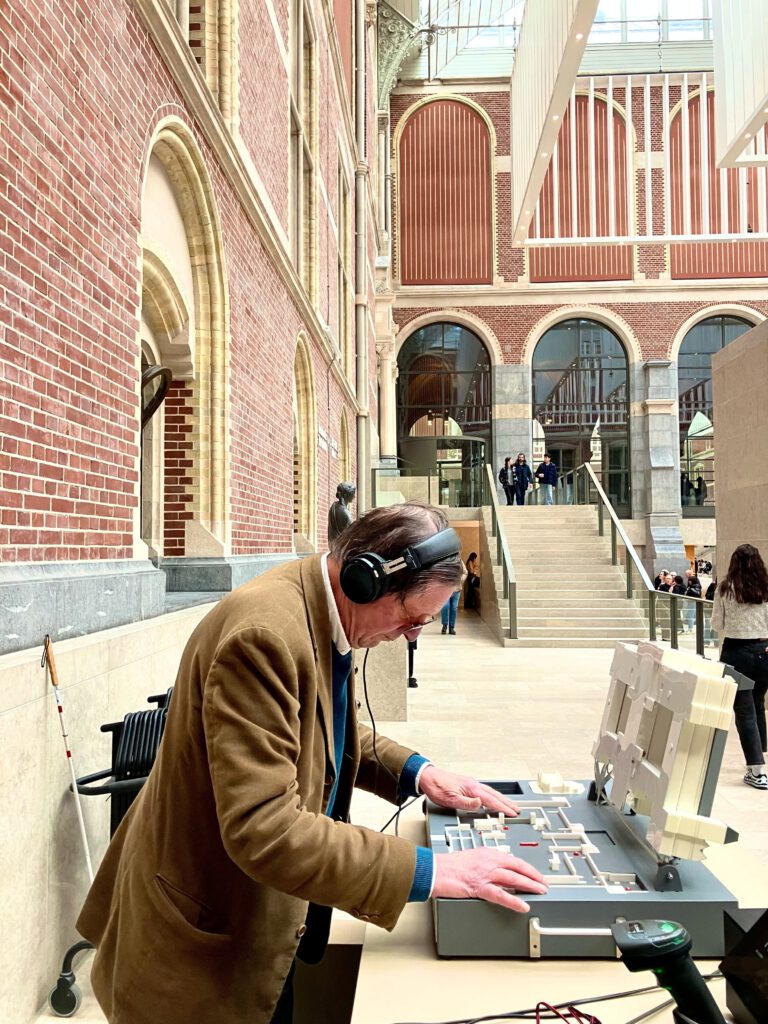 Een blinde man staat in de aula van het museum en verkent aandachtig het opengeklapte model met zijn handen