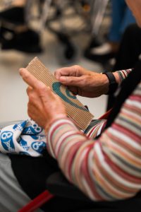 Twee handen betasten de structuur van een papierkunstwerk.