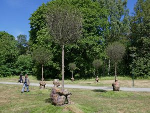 Manfiguren van Jaume Plensa omarmen meerdere bomen.