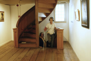 Blinde vrouw loopt door het Voerman Museum Hattem terwijl ze luistert naar de 3D-audiotour.