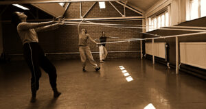 Dansers in een studio in de weer met lange linten.