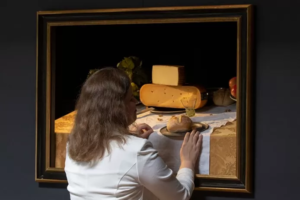 Vrouw betast schilderij met etenswaren met haar handen