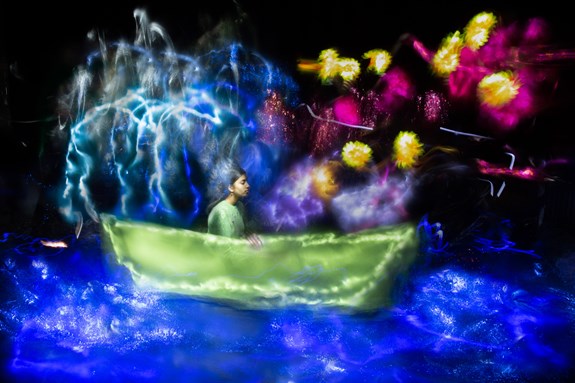 Jonge vrouw zittend in een boot verlicht door felle kleuren 