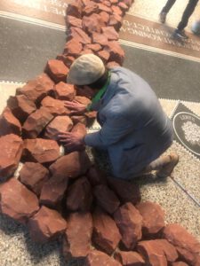 Blinde man voelt aan de stenen van het kunstwerk: "River Of Stones".