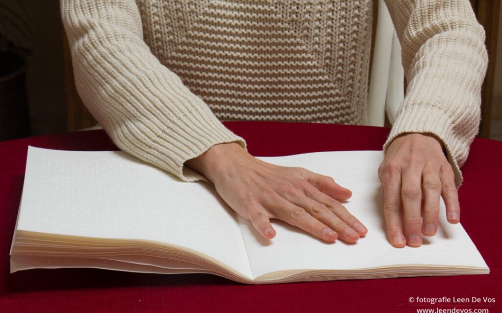 Een slechtziend persoon leest een braille tekst uit een boek