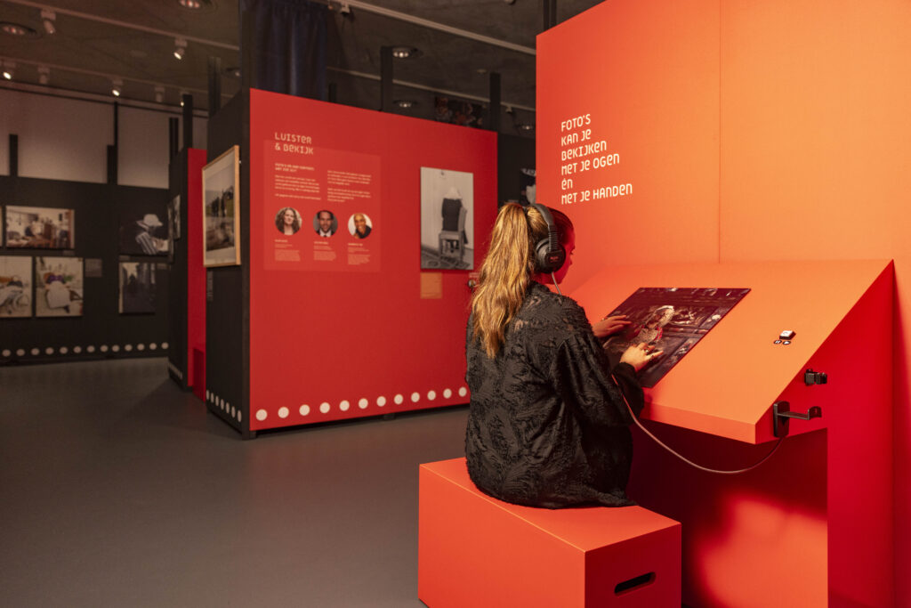 Bezoeker die reliëffoto van Jimmy Nelson voelt en luistert naar audio