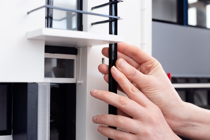 Twee handen onderzoeken de voelmaquette van het Rietveld-Schroder huis