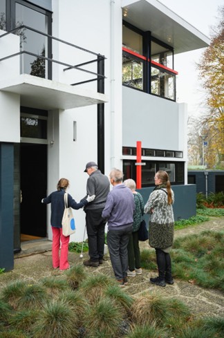 Een groep slechtziende mensen met taststokken betreden het Rietveld-Schroder huis